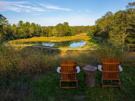 Exclusive relaxation package with serene pond view at The Preserve Resort and Spa, Rhode Island, featuring comfortable Adirondack chairs.