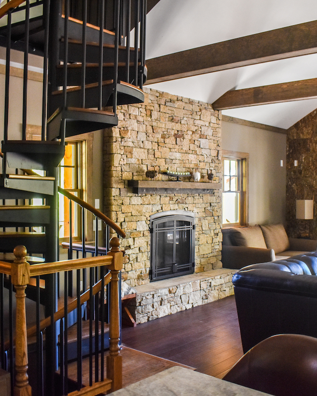 Cozy cabin interior with a spiral staircase and stone fireplace at Event Venue at The Preserve Resort & Spa in Rhode Island, offering a warm and inviting atmosphere.
